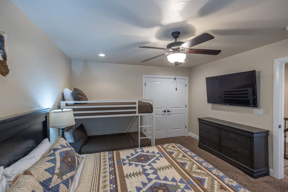 Bedroom 5 Side View - Bedroom 5 has a king bed with twin over twin bunk bed and a 55 inch TV.  There are power stations on the nightstands with power outlet and USB ports for easy charging or power access.