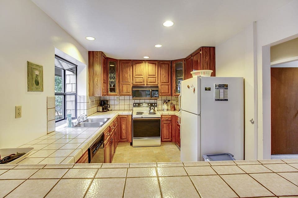 Fully stocked kitchen, tile counters, and convenient pass through to the dining area.
