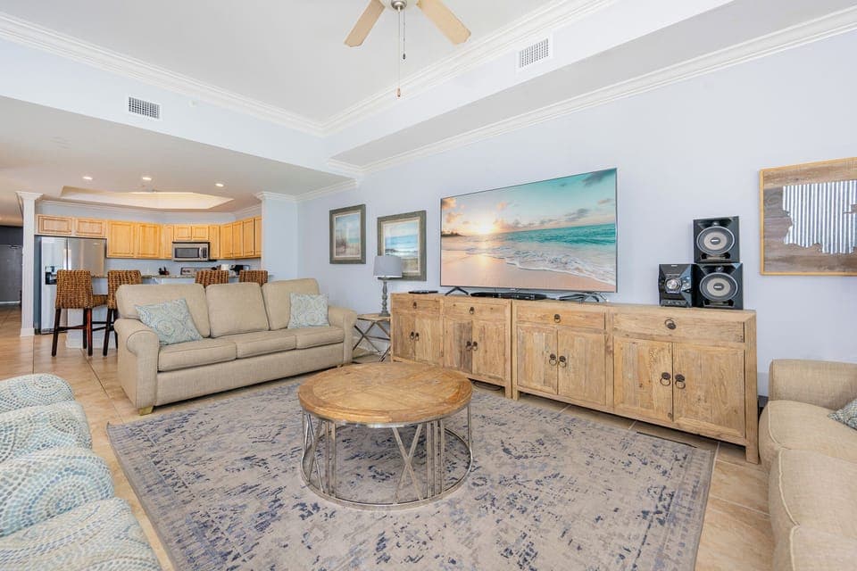 Bright living area featuring two cozy sofas with two queen sleepers, large TV, and a view of the stylish kitchen area