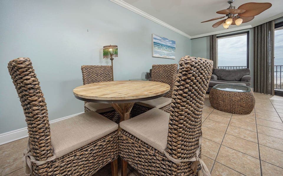 Gather around the round dining table with woven chairs, enjoying the inviting coastal decor and natural light