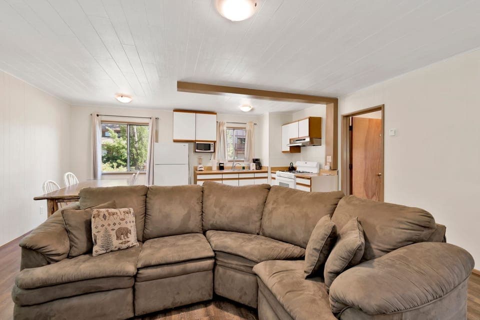 Cozy cabin living room with a stone fireplace, comfy seating, and a TV—perfect for relaxing evenings, movie nights, and unforgettable mountain getaways.