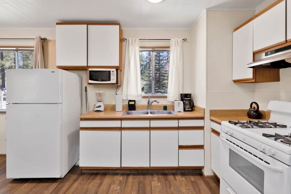 Kitchen with a refrigerator, stove, microwave, oven, toaster, coffee machine, blender, and a dining table to enjoy a delicious meal.