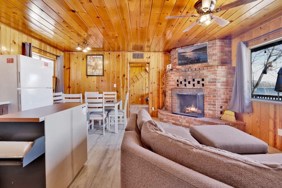 Cozy cabin living room with a stone fireplace, comfy seating, and rustic wood details—perfect for relaxing evenings, movie nights, and unforgettable mountain getaways.