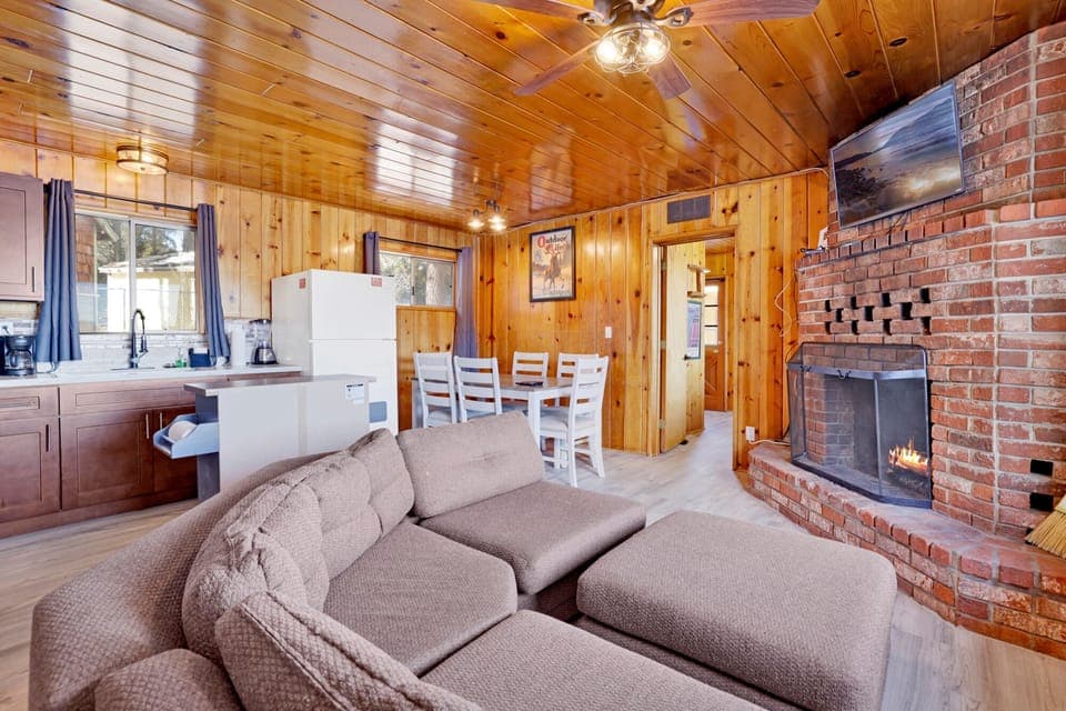 Cozy cabin living room with a stone fireplace, comfy seating, and rustic wood details—perfect for relaxing evenings, movie nights, and unforgettable mountain getaways.