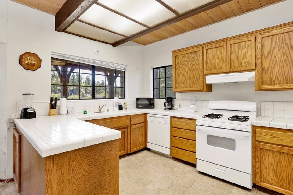 Fully equipped cabin kitchen with warm wood cabinets, stove, fridge, microwave, and coffee maker—perfect for cooking meals, morning coffee, and feeling right at home on your stay.