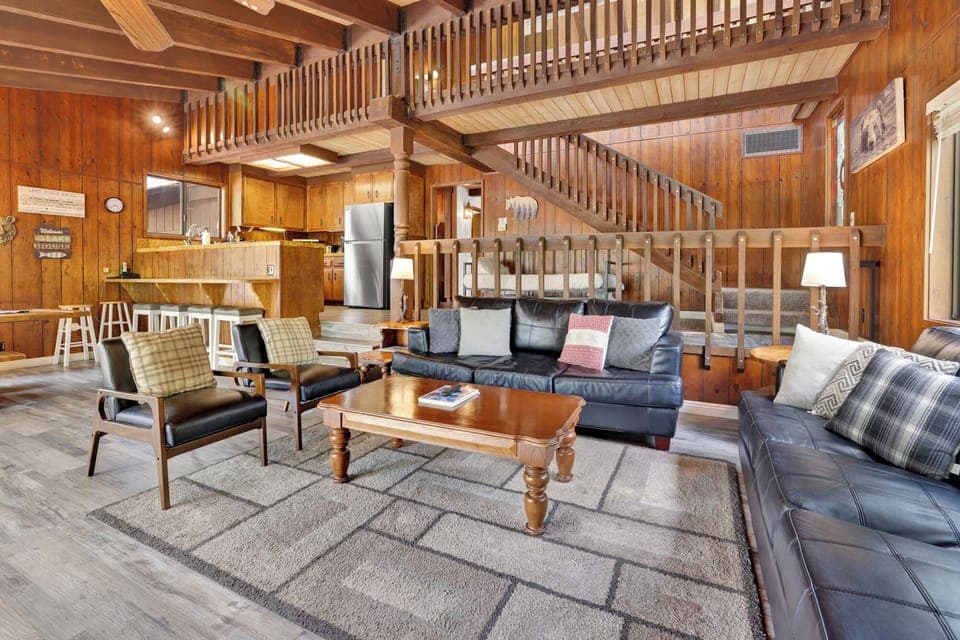 Cozy mountain living room with wood ceilings, stone fireplace, comfy seating —perfect for relaxing evenings, movie nights, and warm cabin vibes after outdoor adventures.