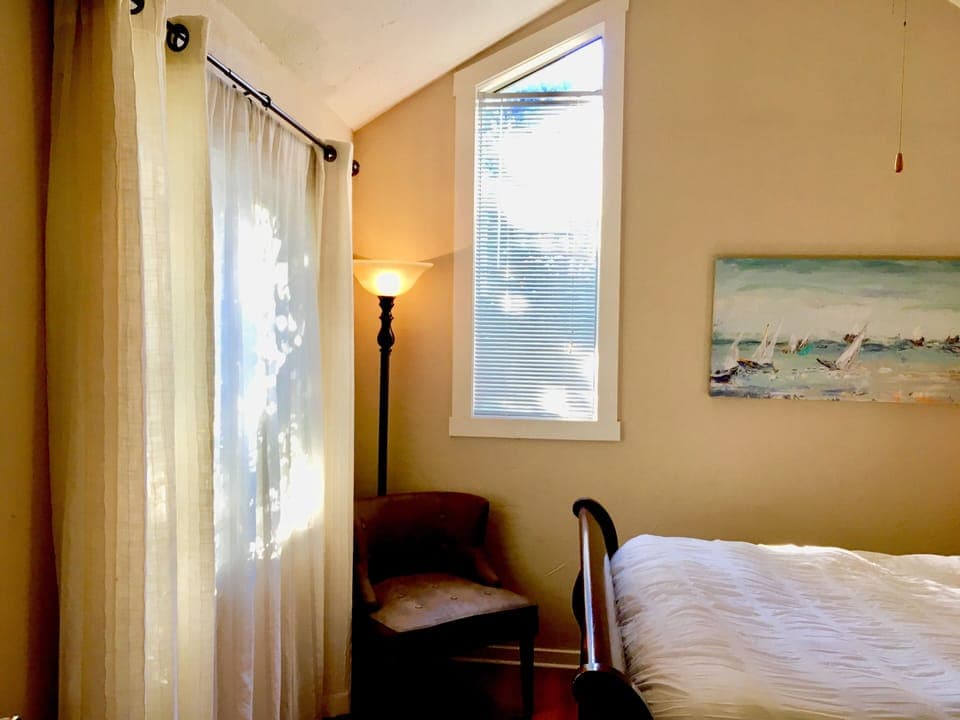 The view is into the garden. Bedroom features a closet with hangers and dresser.