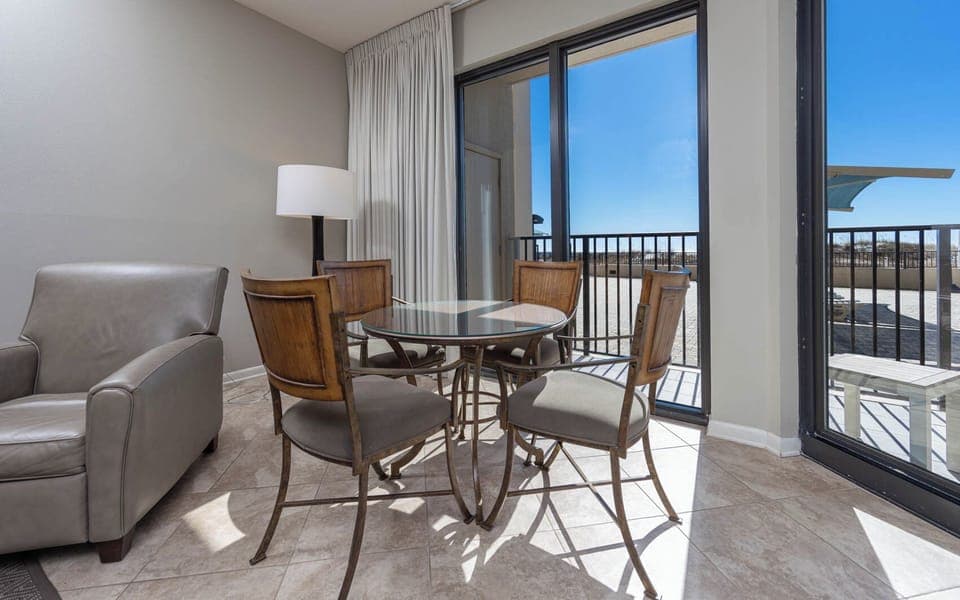 Dine at the glass-top table surrounded by stylish chairs, with natural light streaming in from the patio