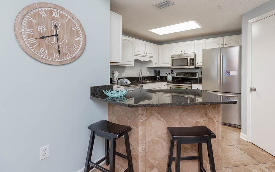 Gather around the stylish bar area with sleek stools, perfect for casual meals and conversations in the inviting kitchen