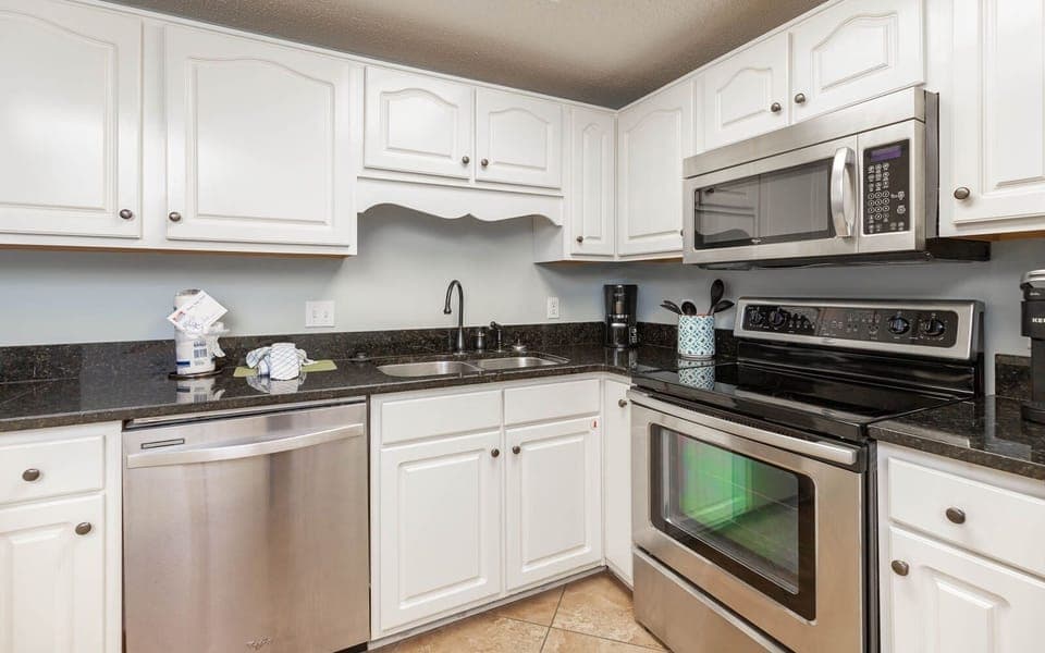 Prepare meals in the stylish kitchen, featuring stainless appliances, ample counter space, and white cabinetry