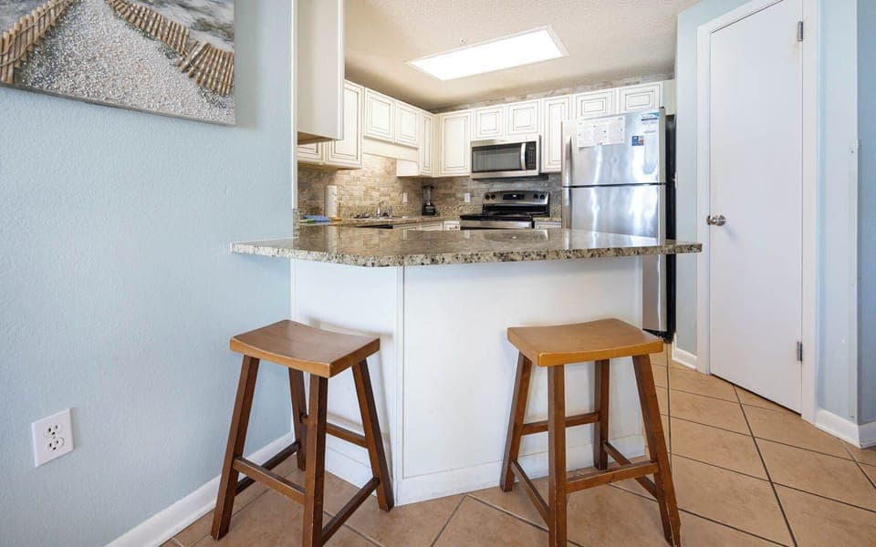 Gather around the granite counter with two stools, perfect for casual meals in a welcoming kitchen space