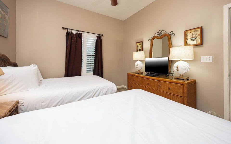 Rest in this inviting guest bedroom featuring two double beds, a TV, and warm lighting for a relaxing stay