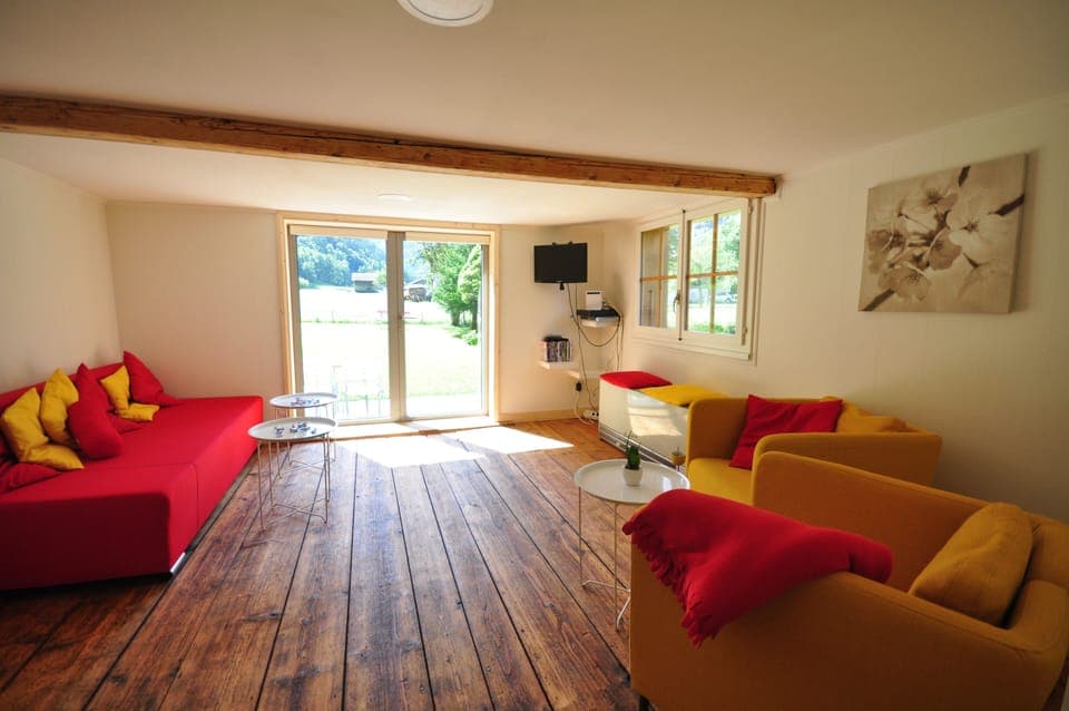 Light spacious lounge with double doors leading to garden patio.  Red sofabed.