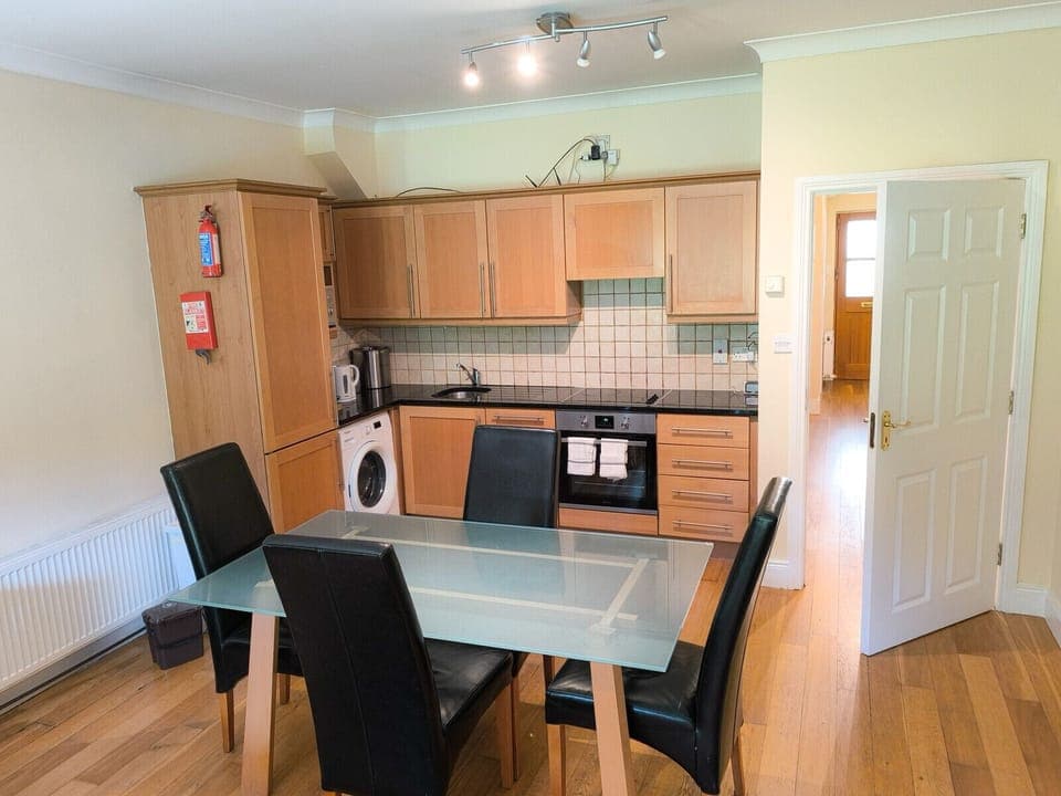 Heyward Mews Holiday Homes, Modern bright kitchen, wooden flooring. Dining table and chairs.