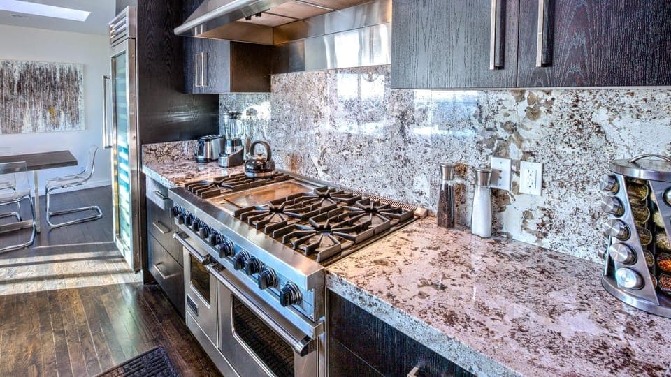 Dark modern kitchen w/ 6 burner gas stove, oversized wine cooler, & double ovens