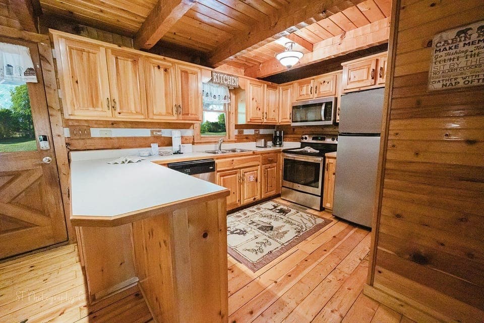 Fully equipped kitchen with stainless steel appliances, kitchen island with sink, and rustic wood accents at A Slice of Heaven cabin in Wears Valley, Tennessee