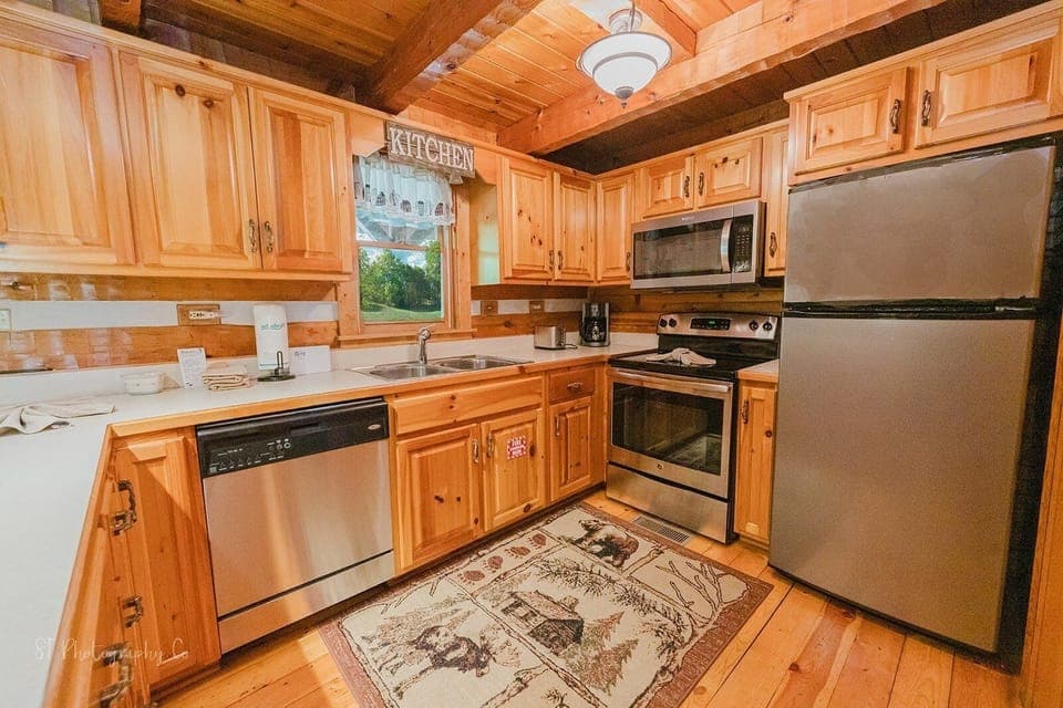 Modern kitchen with stainless steel refrigerator, stove, microwave, and dishwasher at A Slice of Heaven pet friendly cabin in Wears Valley, Tennessee