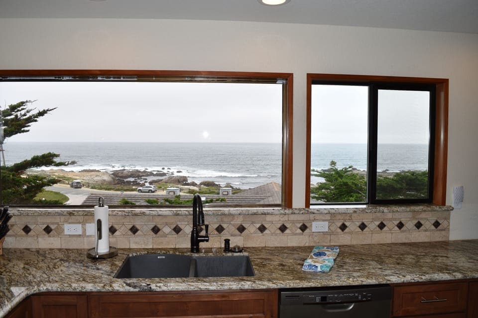 Kitchen sink with granite and tiled backsplash with an ocean view.