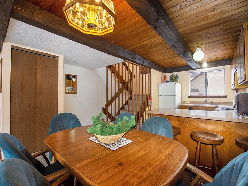 Gather around the warm wood dining table where rustic beams and cozy lighting create perfect moments for your vacation meals together.