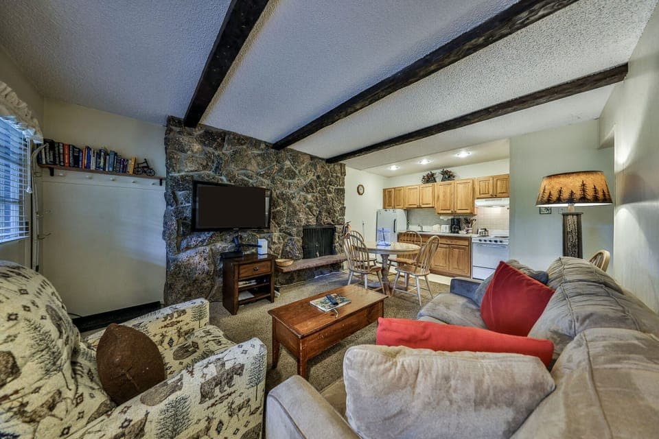 Sink into plush sofas by your stone fireplace, where rustic beams and mountain charm create the perfect retreat for cozy evenings.