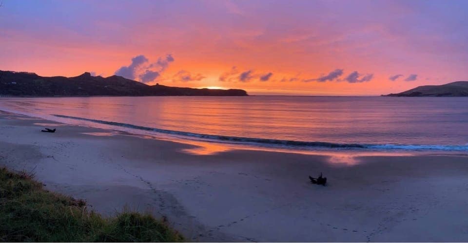 standing on the beach in front of the house 