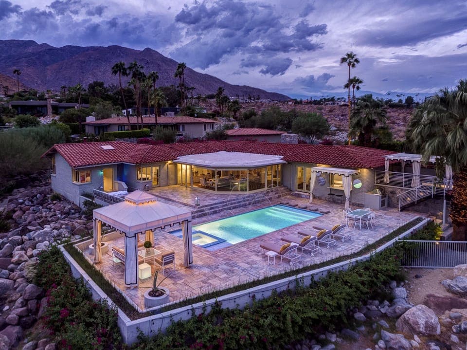 Twilight aerial of rear terrace and poolside cabana seating area.
