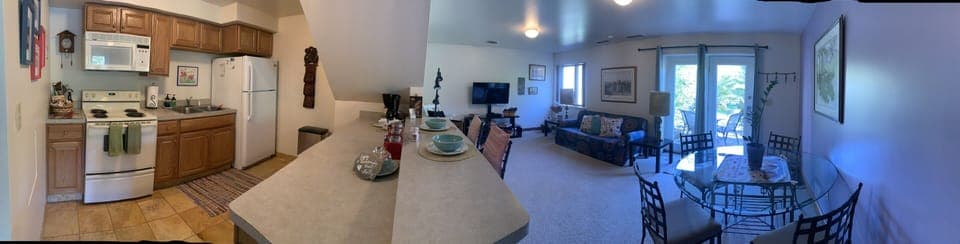 Pano of the fully stocked kitchen, living and dining room overlooking the patio.