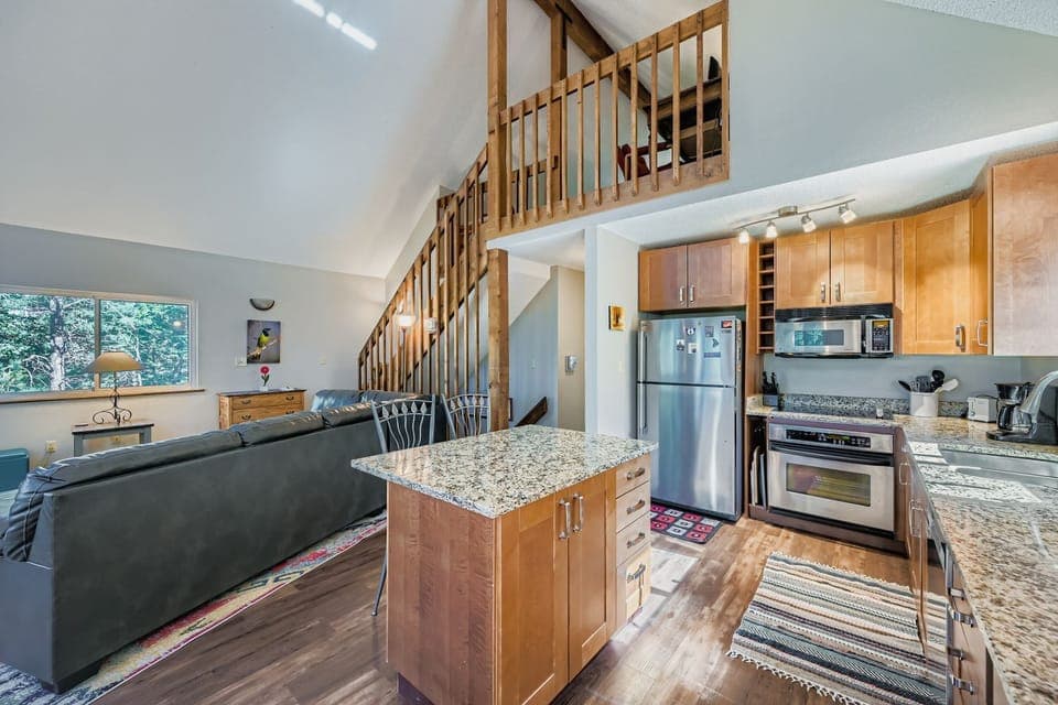 Great room with kitchen and stairs leading to open loft bedroom and lower level