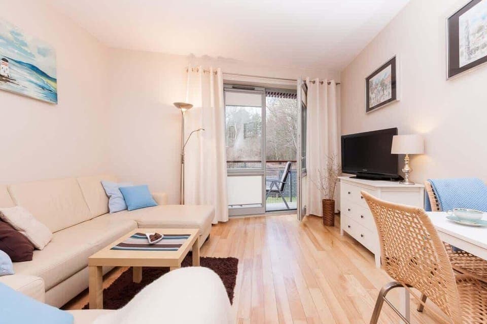 A cozy living room with a light-colored sectional sofa and blue accent pillows. The room also features a wooden coffee table and soft lighting.