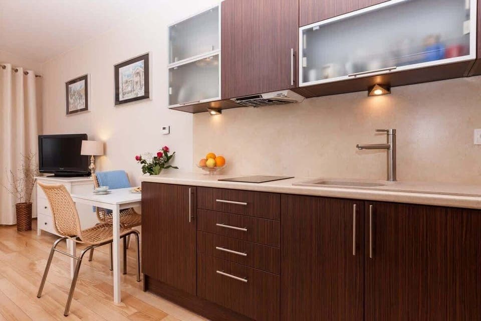 An open living and dining space with a small dining table and a sectional sofa. The lighting is warm, creating an inviting atmosphere.