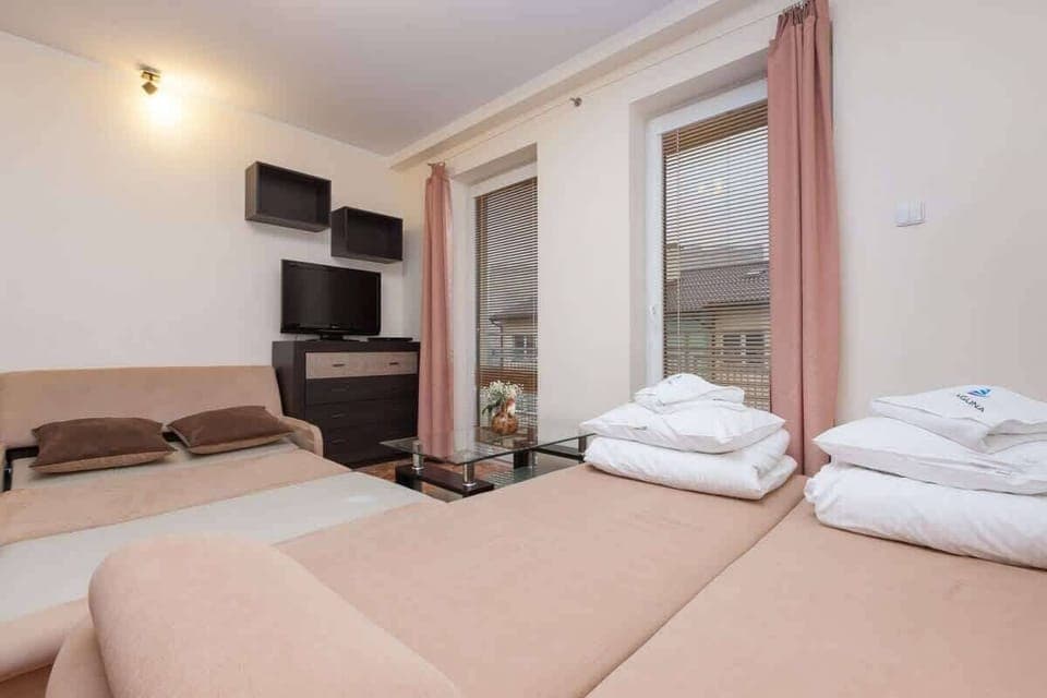 Another angle of the living room with a view of the couch and a folded set of towels placed on the bed in the background. It emphasizes the comfort of the space, blending the bedroom and living area.