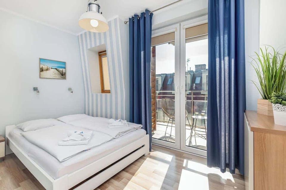 Bright and cosy bedroom with blue curtains and comfortable bed for two people.