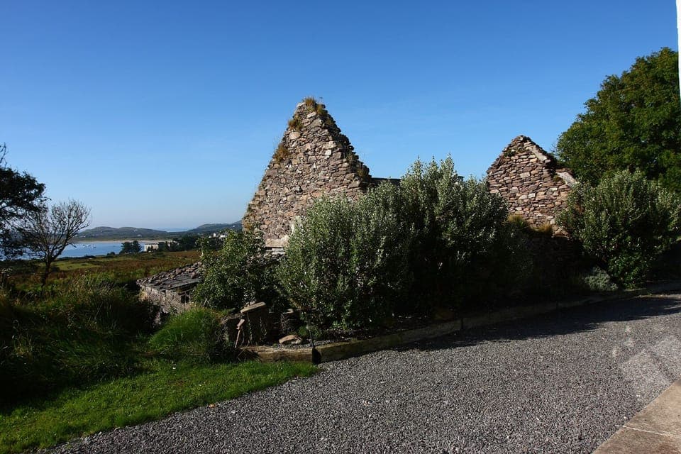 Famine cottage ruin beside house