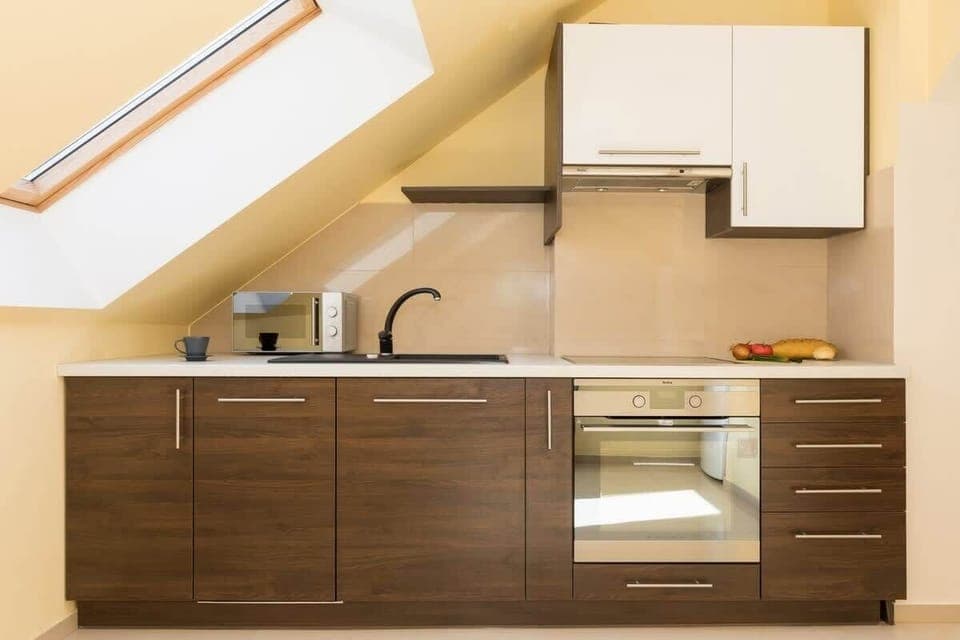 Loft kitchen. Furniture in brown and white. Kitchen has oven, hob and microwave.