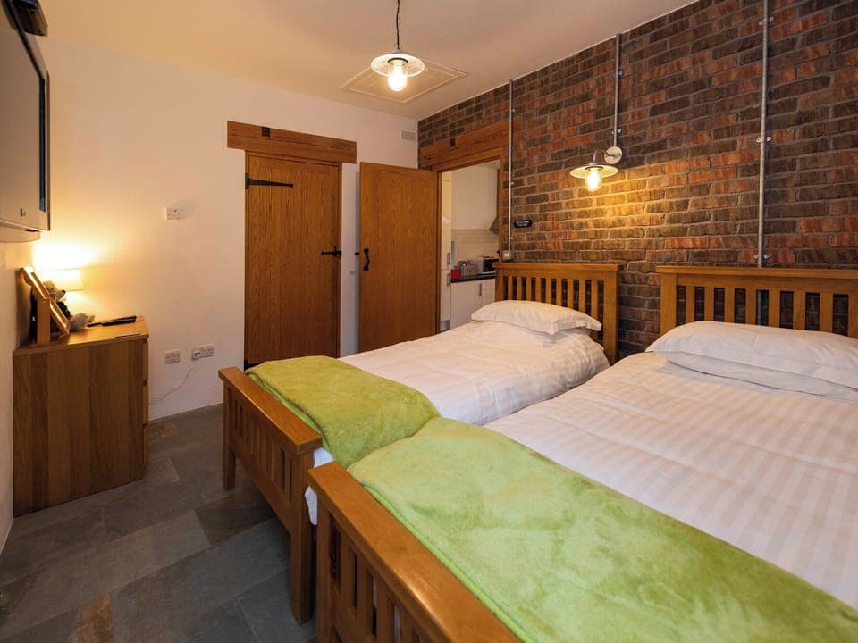The twin bedroom has a stone feature wall | Cart Shed, Mauchline, near Ayr