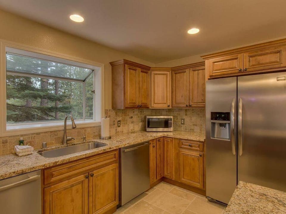 Cozy kitchen with stainless steel appliances and forest views