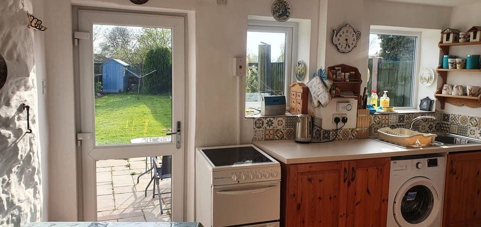 Bright kitchen leading to patio and fenced garden 