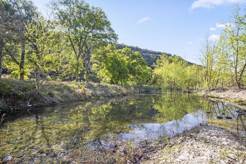 Peaceful creekside retreat with crystal-clear water and lush hill country views-perfect for relaxing or exploring nature.