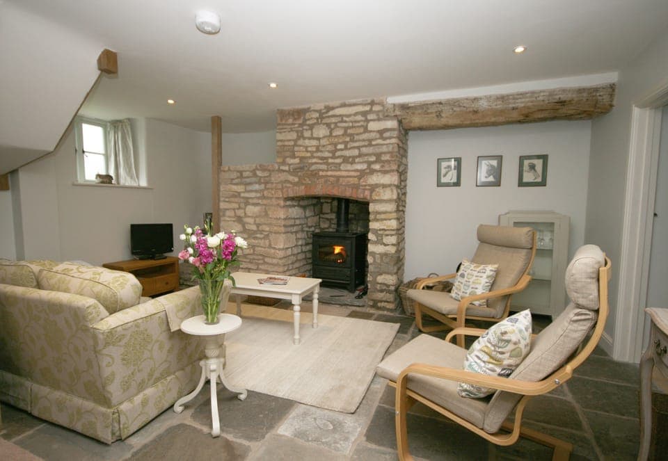 Sitting room with wood-burner and circular stone staircase hidden in the corner.