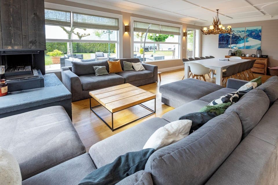 Large living / dining space with comfy couches by the fireplace and lake views