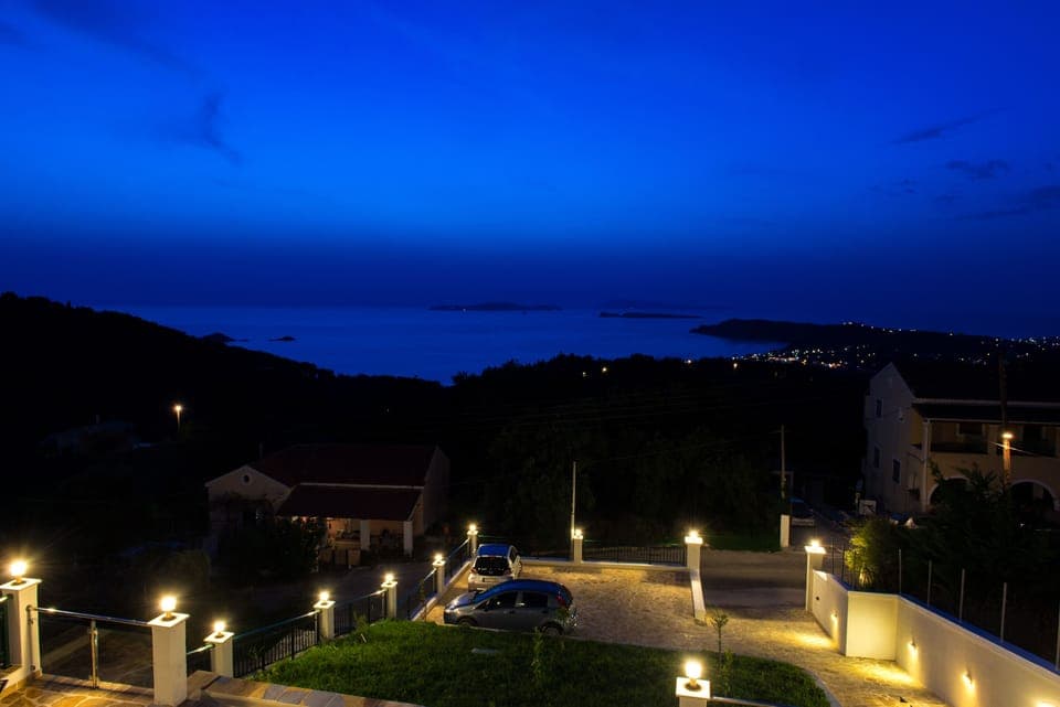 Night views to Arillas from 1st floor terrace also showing parking area below.
