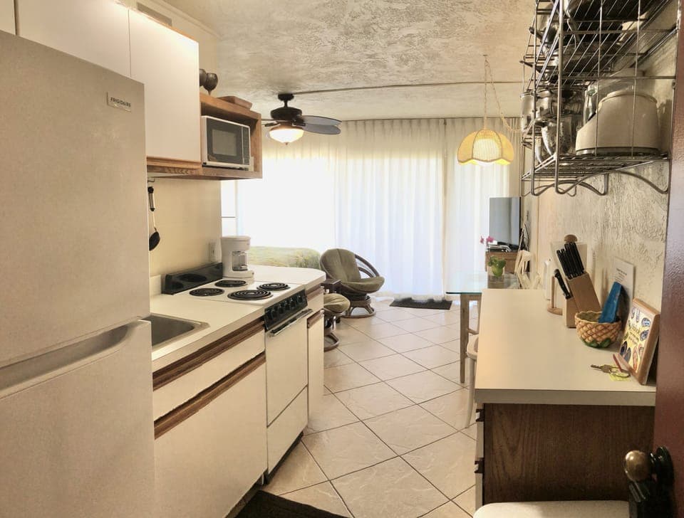 Compact kitchen fully stocked with useful appliances, utensils, pots and pans.