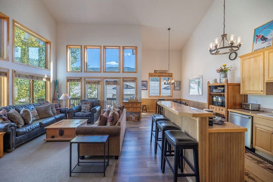 Great Room has two walls of high windows (framing the top half of the ski runs).