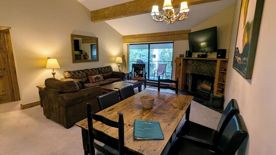 Living room with sofa bed, wood fireplace, dining table, and balcony w/ gas BBQ