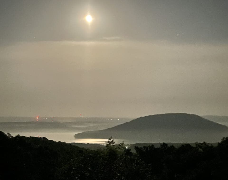 Peaceful night, moon shining through the clouds and the lights across the lake.