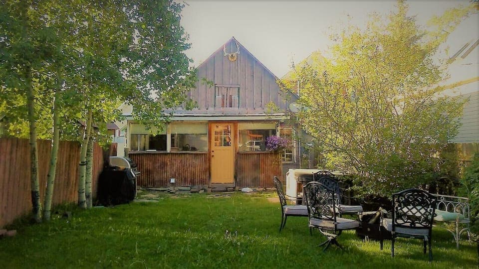 Large backyard equipped with firepit, loan chairs and grill.
