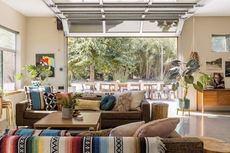 Roll up glass garage door in living room that connects blends inside/outside spaces.  