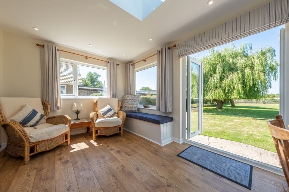 Tanholt, Holme-next-the-Sea: The sun room with comfortable seating looking out into the garden