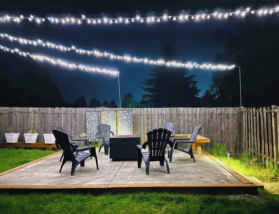 Gorgeous outdoor seating area next to cozy fire pit, flower boxes & lights above