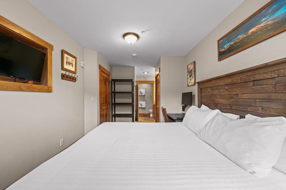 Primary bedroom with king-sized bed, mounted TV, and workspace